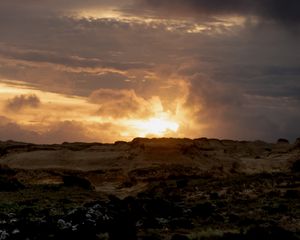 Preview wallpaper sunset, clouds, stones, sand, nature