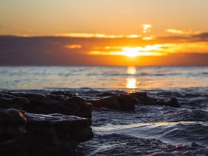 Preview wallpaper sunset, glare, sea, stones, rocks
