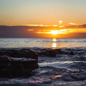 Preview wallpaper sunset, glare, sea, stones, rocks