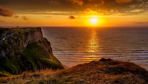 Preview wallpaper sunset, horizon, rock, water surface, grass