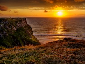 Preview wallpaper sunset, horizon, rock, water surface, grass