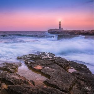 Preview wallpaper sunset, lighthouse, sea, surf, waves, stones, spain