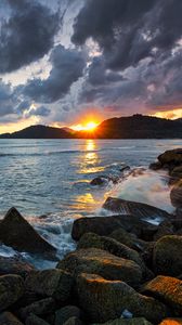 Preview wallpaper sunset, rays, coast, sea, stones