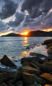 Preview wallpaper sunset, rays, coast, sea, stones