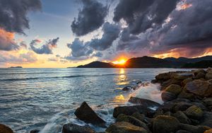 Preview wallpaper sunset, rays, coast, sea, stones