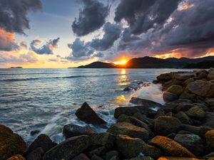 Preview wallpaper sunset, rays, coast, sea, stones