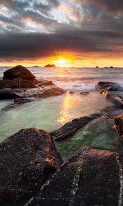 Preview wallpaper sunset, rays, stones, sea, rocks