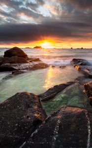Preview wallpaper sunset, rays, stones, sea, rocks