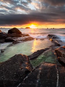 Preview wallpaper sunset, rays, stones, sea, rocks