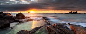 Preview wallpaper sunset, rays, stones, sea, rocks