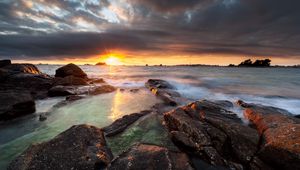 Preview wallpaper sunset, rays, stones, sea, rocks