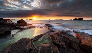 Preview wallpaper sunset, rays, stones, sea, rocks
