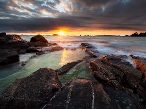 Preview wallpaper sunset, rays, stones, sea, rocks