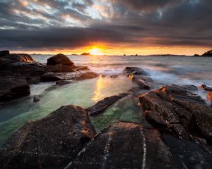 Preview wallpaper sunset, rays, stones, sea, rocks