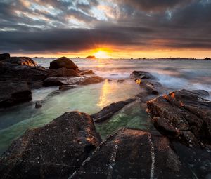 Preview wallpaper sunset, rays, stones, sea, rocks