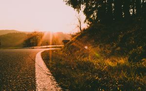 Preview wallpaper sunset, road, forest, grass, glare