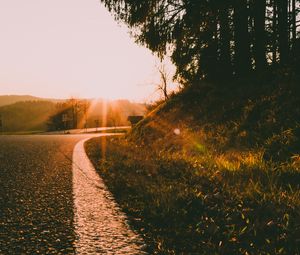 Preview wallpaper sunset, road, forest, grass, glare