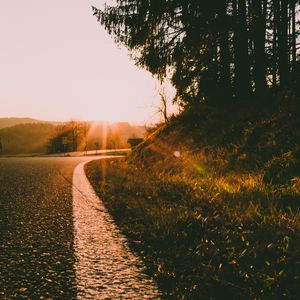 Preview wallpaper sunset, road, forest, grass, glare