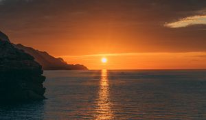 Preview wallpaper sunset, rocks, glare, sea, horizon