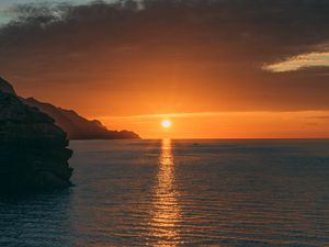 Preview wallpaper sunset, rocks, glare, sea, horizon