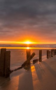 Preview wallpaper sunset, sea, beach, pillars, sand