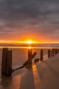 Preview wallpaper sunset, sea, beach, pillars, sand