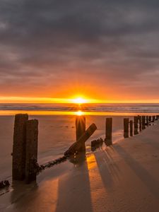 Preview wallpaper sunset, sea, beach, pillars, sand