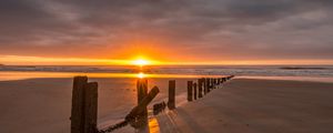 Preview wallpaper sunset, sea, beach, pillars, sand