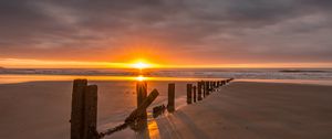 Preview wallpaper sunset, sea, beach, pillars, sand