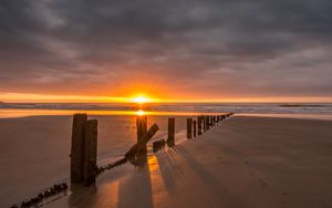 Preview wallpaper sunset, sea, beach, pillars, sand