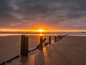 Preview wallpaper sunset, sea, beach, pillars, sand