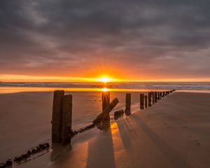 Preview wallpaper sunset, sea, beach, pillars, sand