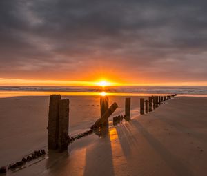 Preview wallpaper sunset, sea, beach, pillars, sand