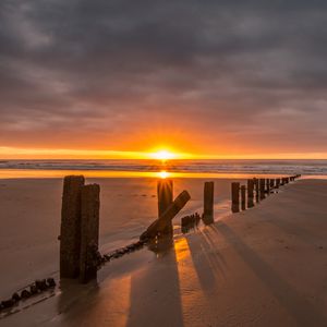 Preview wallpaper sunset, sea, beach, pillars, sand