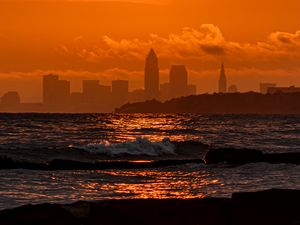 Preview wallpaper sunset, sea, city, dark, waves, horizon