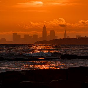 Preview wallpaper sunset, sea, city, dark, waves, horizon