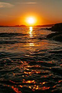 Preview wallpaper sunset, sea, glare, rocks, sky