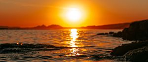 Preview wallpaper sunset, sea, glare, rocks, sky