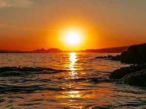 Preview wallpaper sunset, sea, glare, rocks, sky