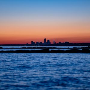 Preview wallpaper sunset, water, city, buildings, silhouettes, dark