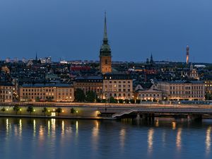 Preview wallpaper tower, buildings, lights, embankment, river, twilight