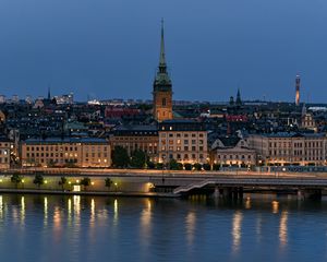 Preview wallpaper tower, buildings, lights, embankment, river, twilight