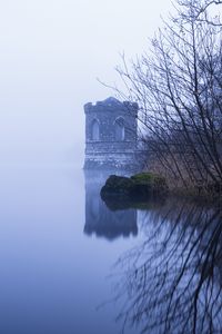 Preview wallpaper tower, lake, reflection, tree, branches, fog