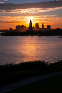 Preview wallpaper towers, skyscrapers, silhouettes, sea, sunset, dark