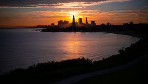 Preview wallpaper towers, skyscrapers, silhouettes, sea, sunset, dark