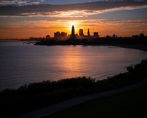 Preview wallpaper towers, skyscrapers, silhouettes, sea, sunset, dark