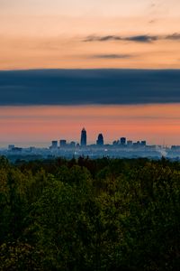 Preview wallpaper trees, city, twilight, view, tops, clouds