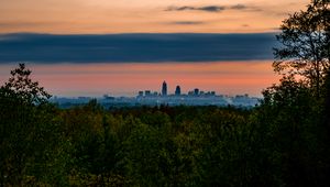 Preview wallpaper trees, city, twilight, view, tops, clouds
