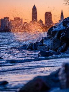 Preview wallpaper water, waves, spray, stones, city, sunset