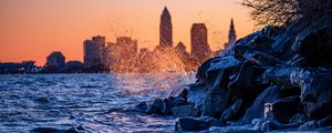 Preview wallpaper water, waves, spray, stones, city, sunset